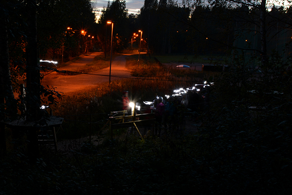 Seikkailijoita harjoitusradalla otsalamppujen valossa Huipun pimeessä seikkailussa.