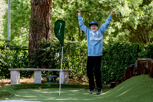 Adventure golf and the joy of succeeding. A boy jumps happily after a successful stroke.
